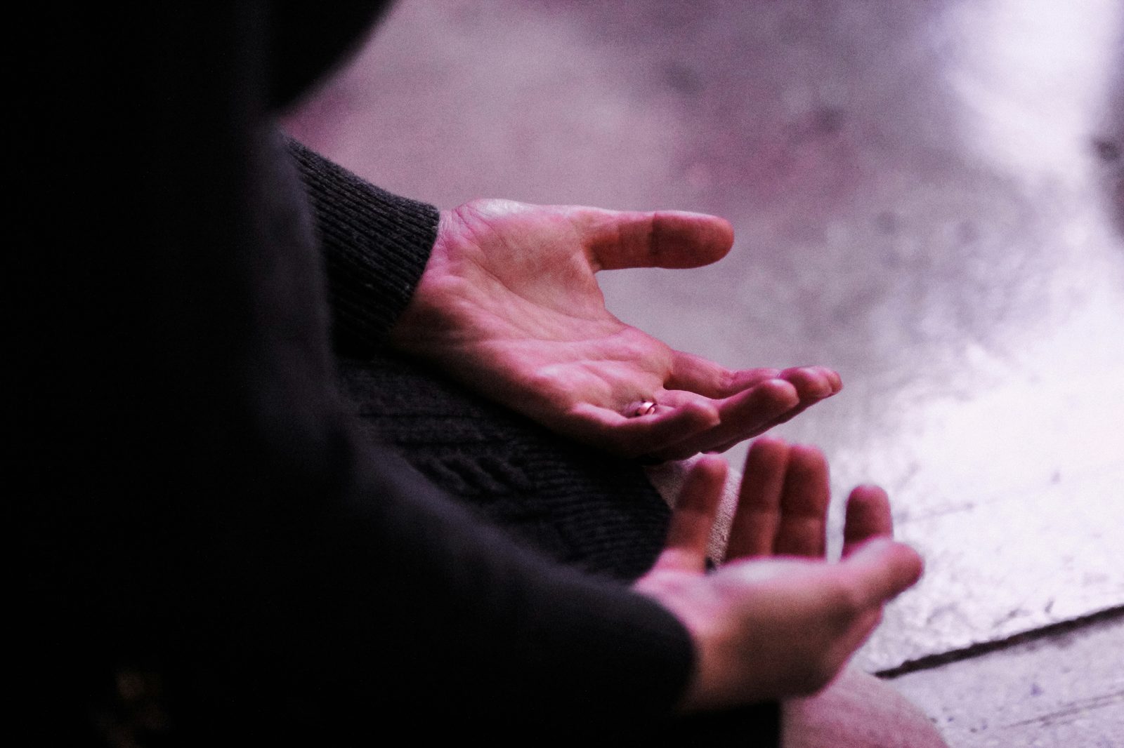 Open hands raised in prayer, lit in soft pink light